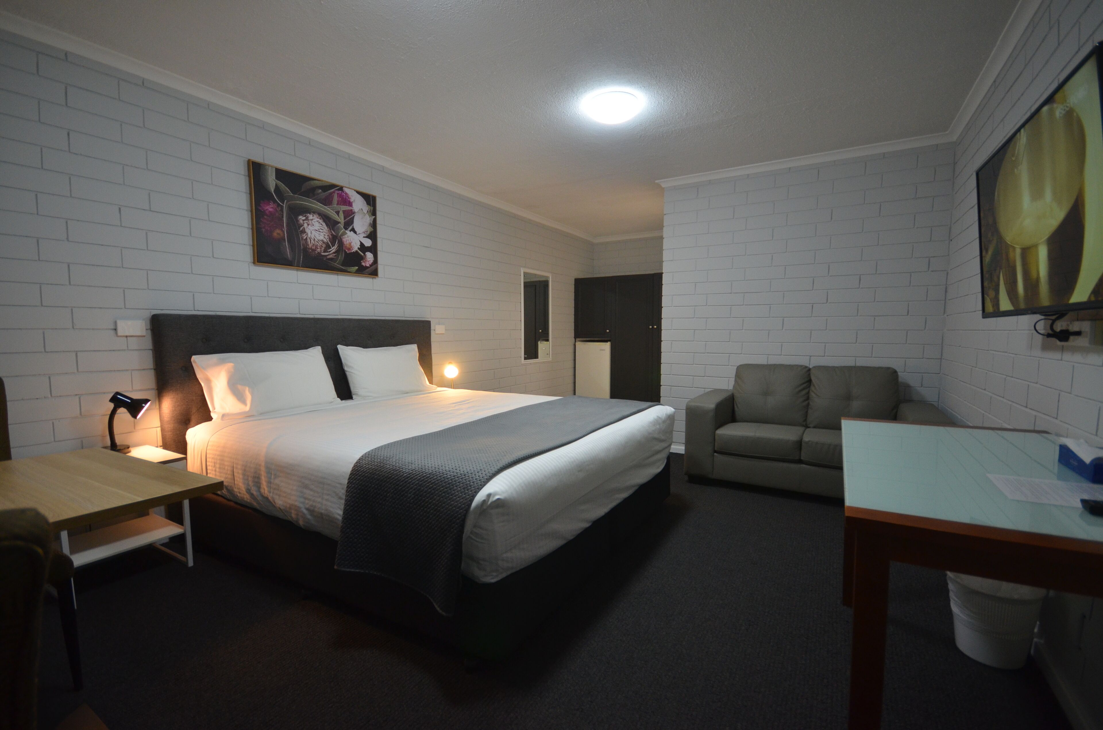 A hotel room with a bed, a desk, a chair, and a sofa.