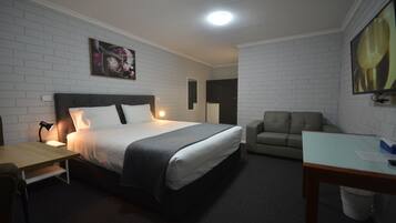 A hotel room with a bed, a desk, a chair, and a sofa.