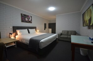 A hotel room with a bed, a desk, a chair, and a sofa.