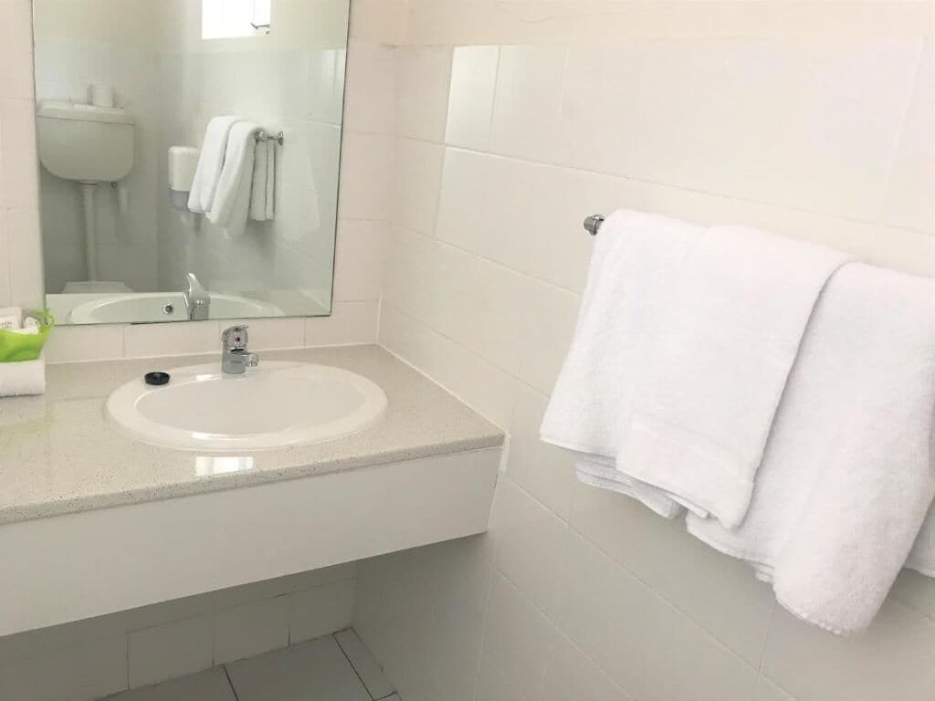 A bathroom with a white sink, a mirror, and a towel rack.