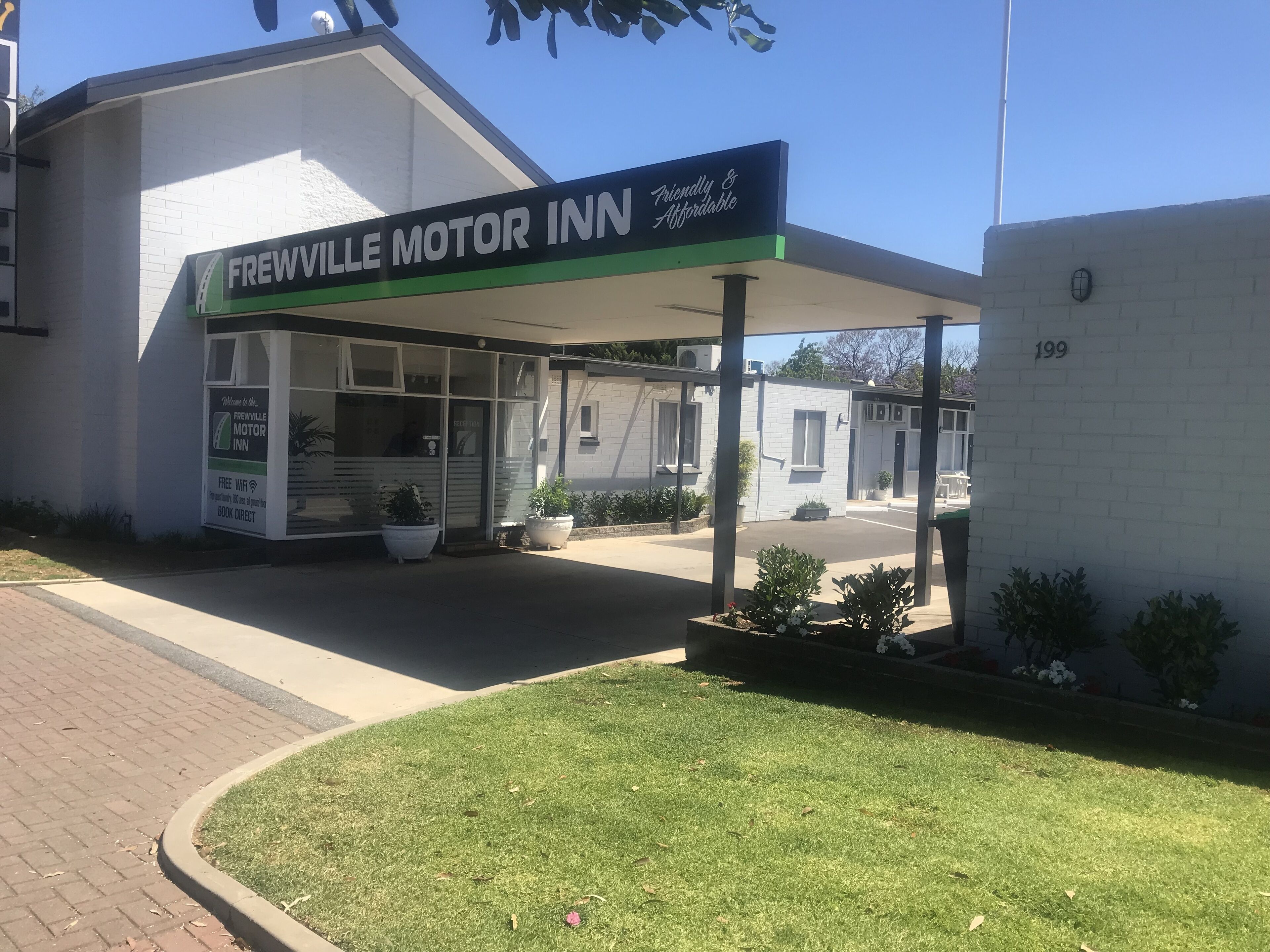 A Frewville Motor Inn with a covered entrance, outdoor seating area, and potted plants.