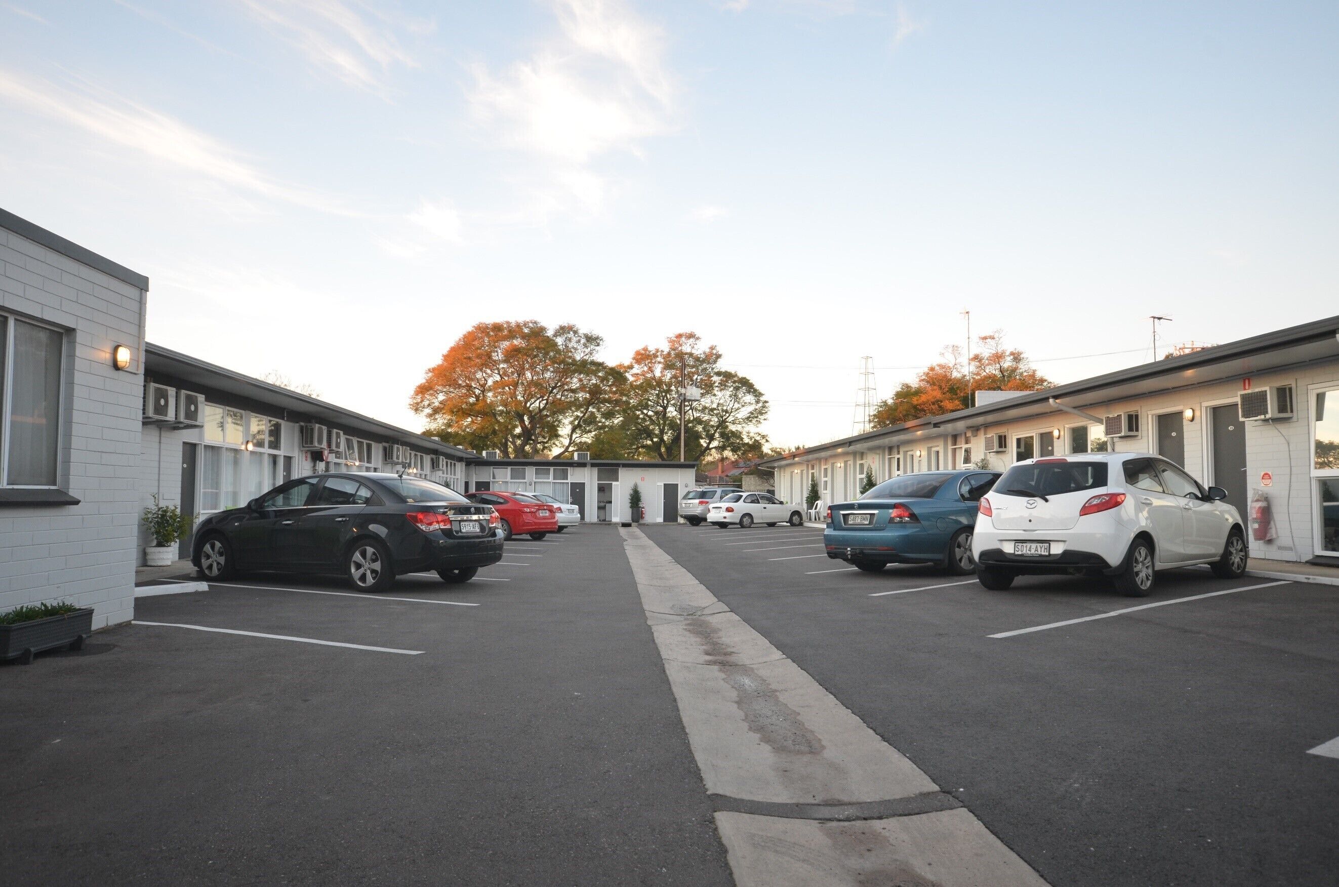 A row of single-story motels with parking spaces in front.
