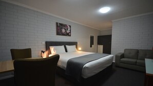 A hotel room with a bed, a desk, a chair, and a sofa. - Frewville Motor Inn (Frewville)