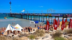 A beach with a pier, tents, and flags. - Frewville Motor Inn (Frewville)