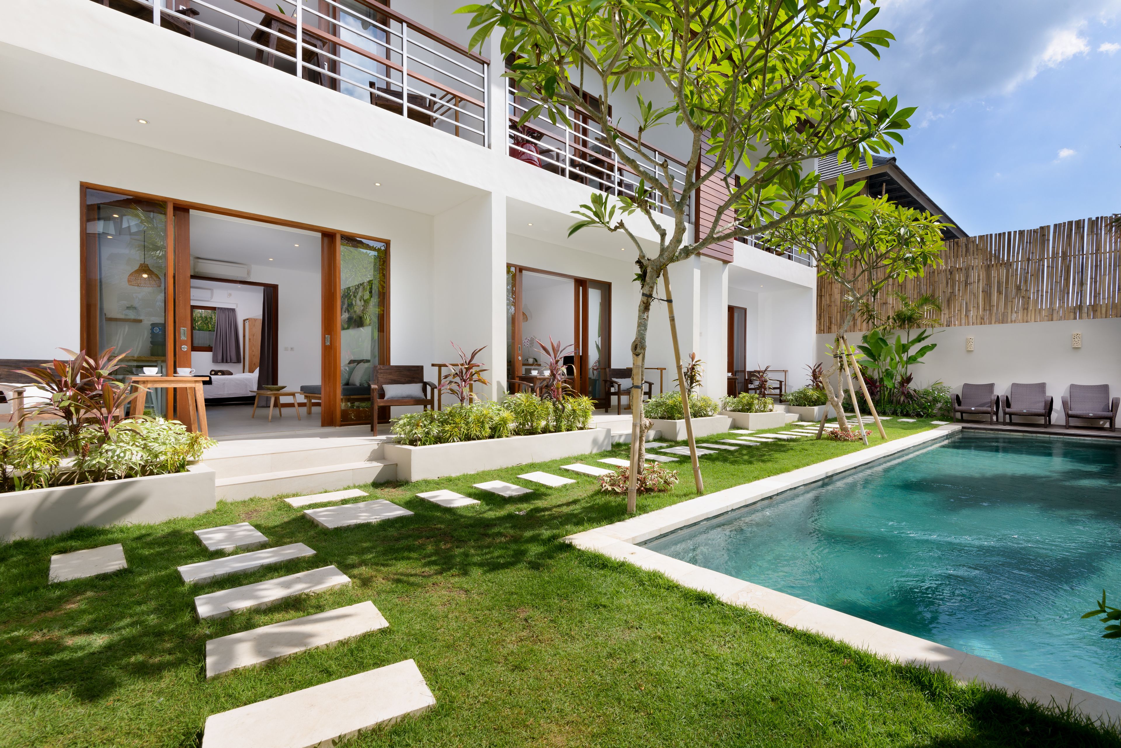 A modern two-story house with a swimming pool, outdoor seating, and a well-maintained garden.