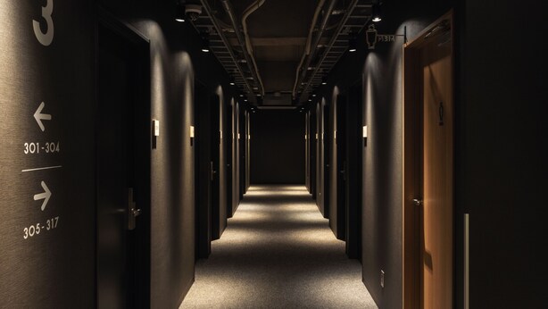A hotel corridor with numbered doors, directional arrows, and a sign indicating the men's restroom. - 9 C Hotel Asahikawa (Asahikawa)