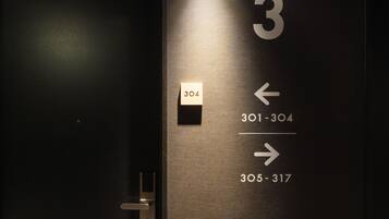 A hotel room door with a number 3 sign and directional arrows indicating room numbers 301-304 and 305-317.