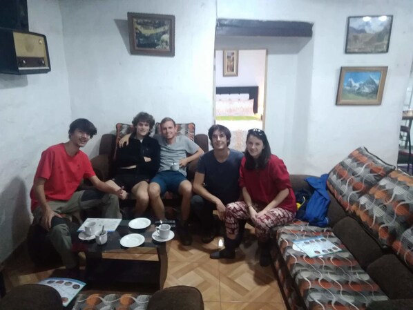 A living room with a sofa, a coffee table with cups and saucers, and a patterned cushion. - Union Wasi 238 (Cusco)