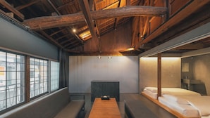 A room with a wooden ceiling, a window with a view of bicycles, a bench, a table, and a bed with white linens. - SEKAI HOTEL Deep Osaka Experience - Hostel (Higashi-osaka)
