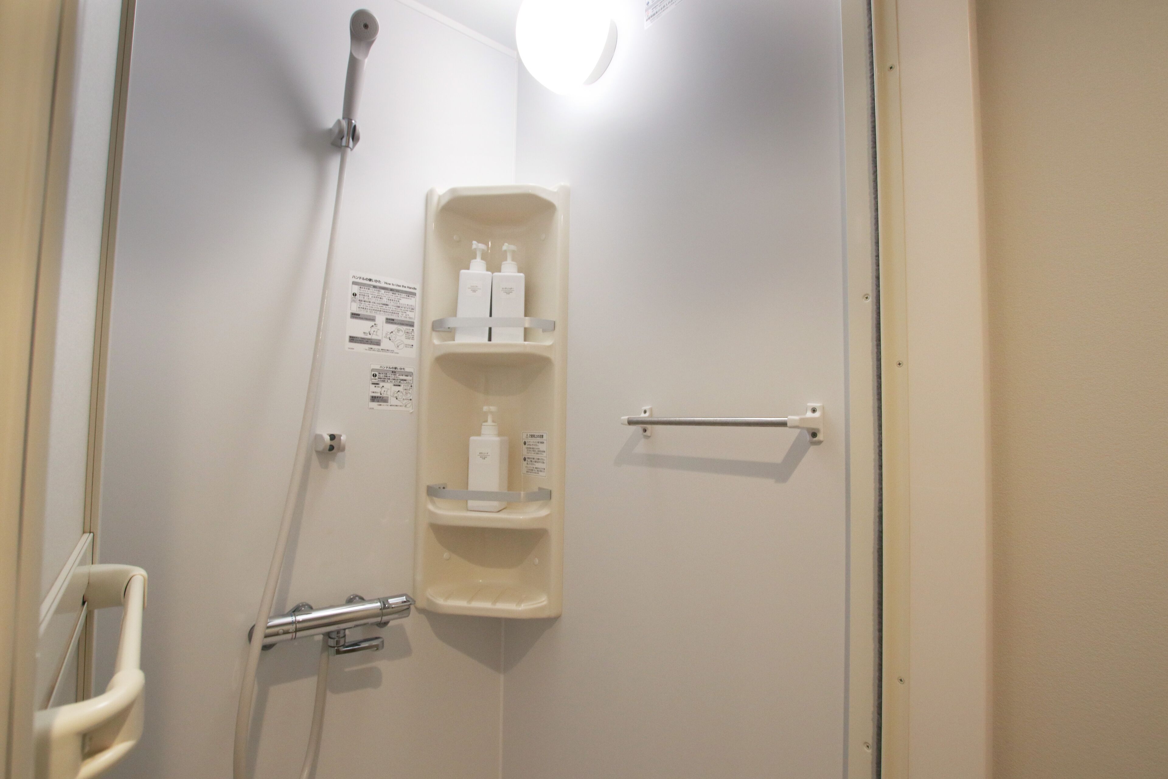 Un baño con ducha, barandilla, toallero y estante con artículos de aseo.