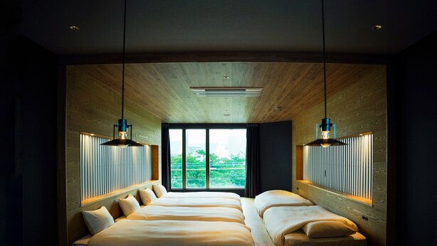A modern bedroom with a large bed, two bedside tables, and a view of greenery through a large window. - SEKAI HOTEL Deep Osaka Experience - Hostel (Higashi-osaka)