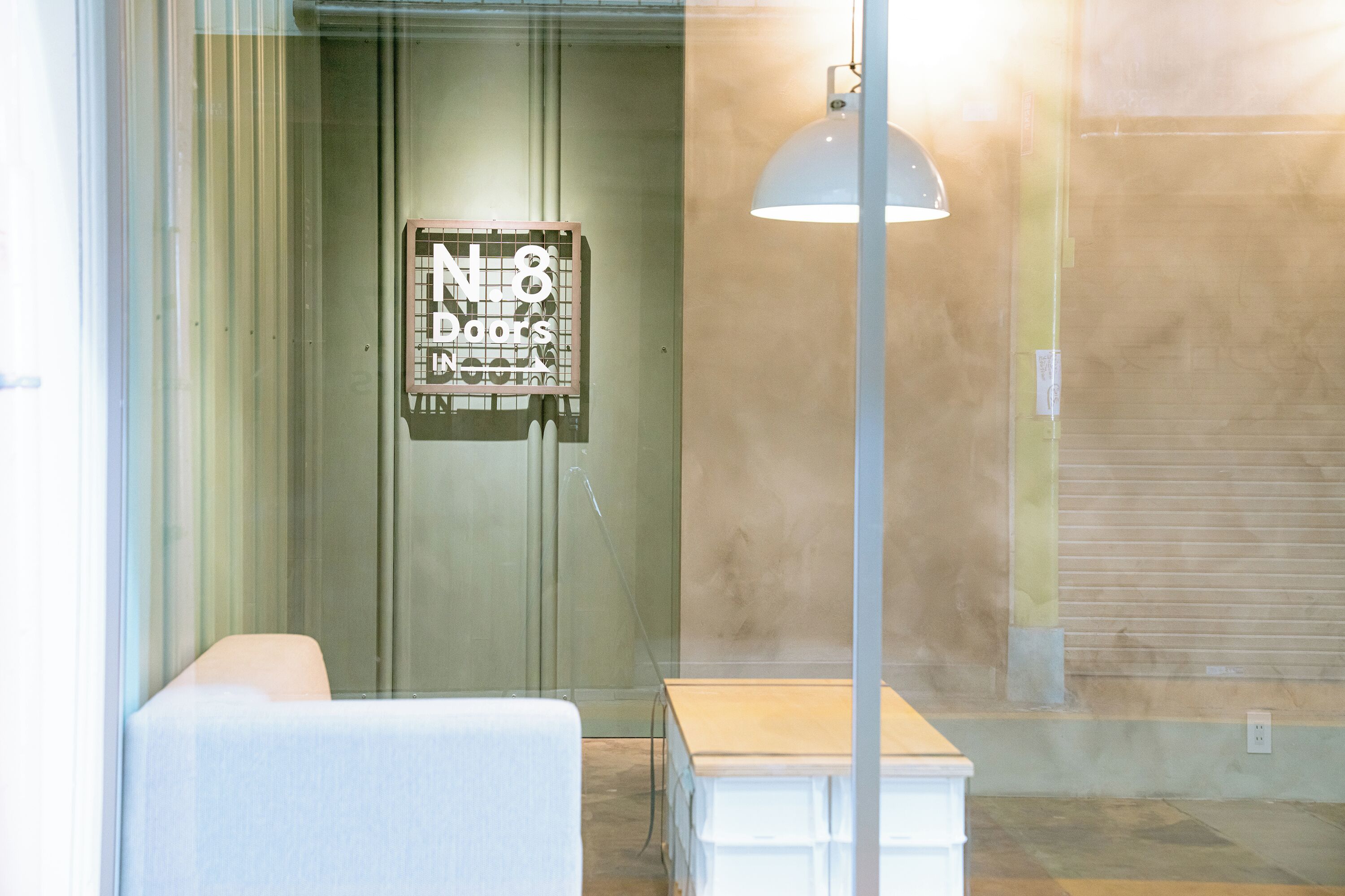 Una habitación con puerta de vidrio, una pequeña mesa y una lámpara.