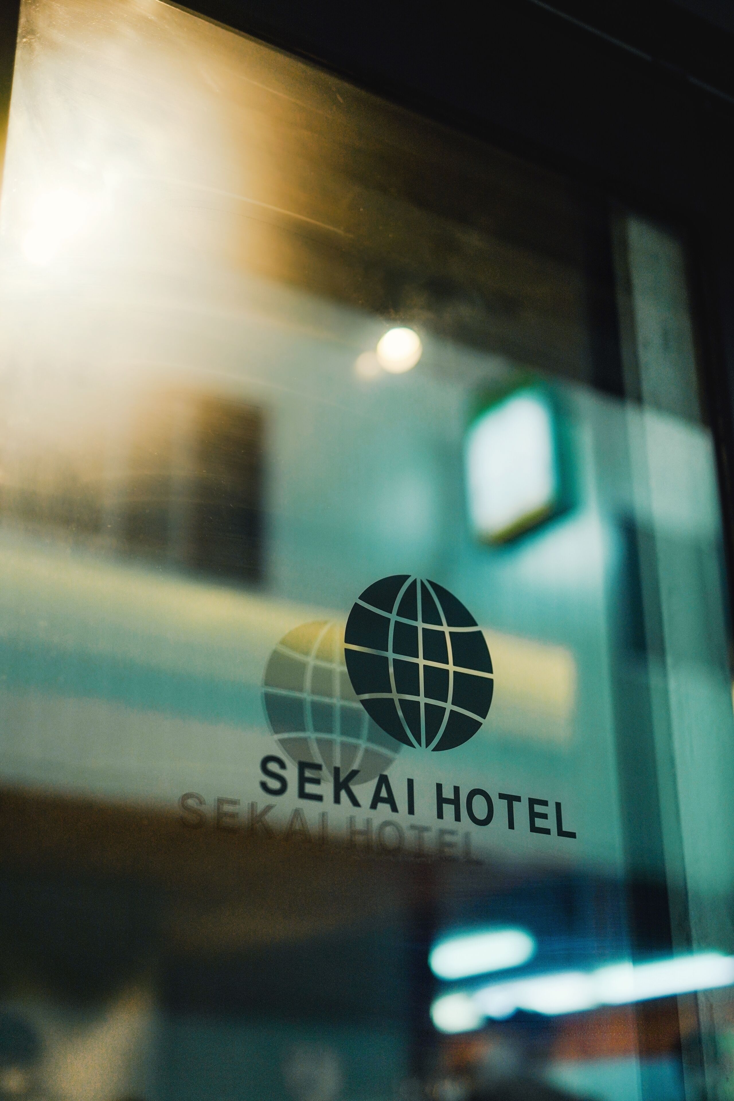Een glazen raam met het logo en de naam van Sekai Hotel.