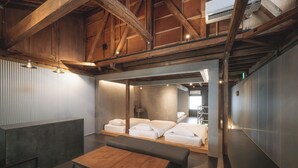 A modern hotel room with a wooden ceiling, a large bed, a bench, and a small table. - SEKAI HOTEL Deep Osaka Experience - Hostel (Higashi-osaka)