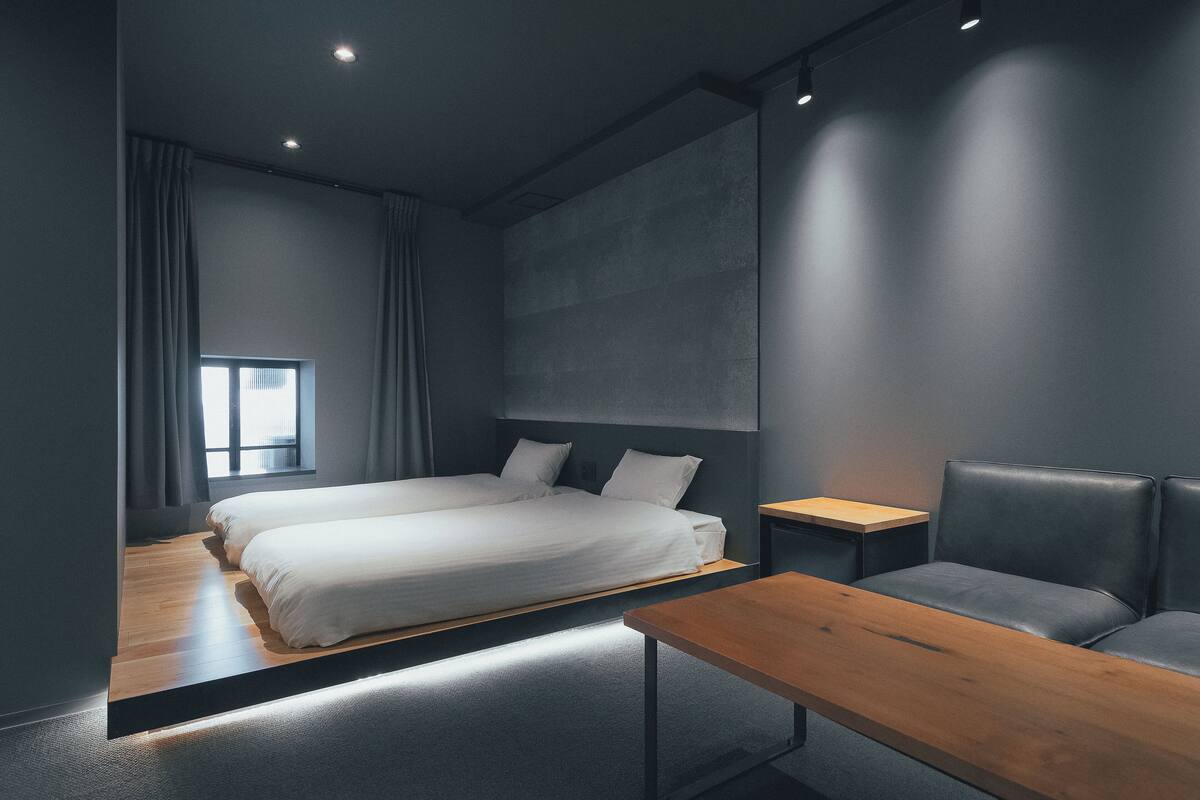A modern hotel room with a large bed, a wooden table, and a seating area.