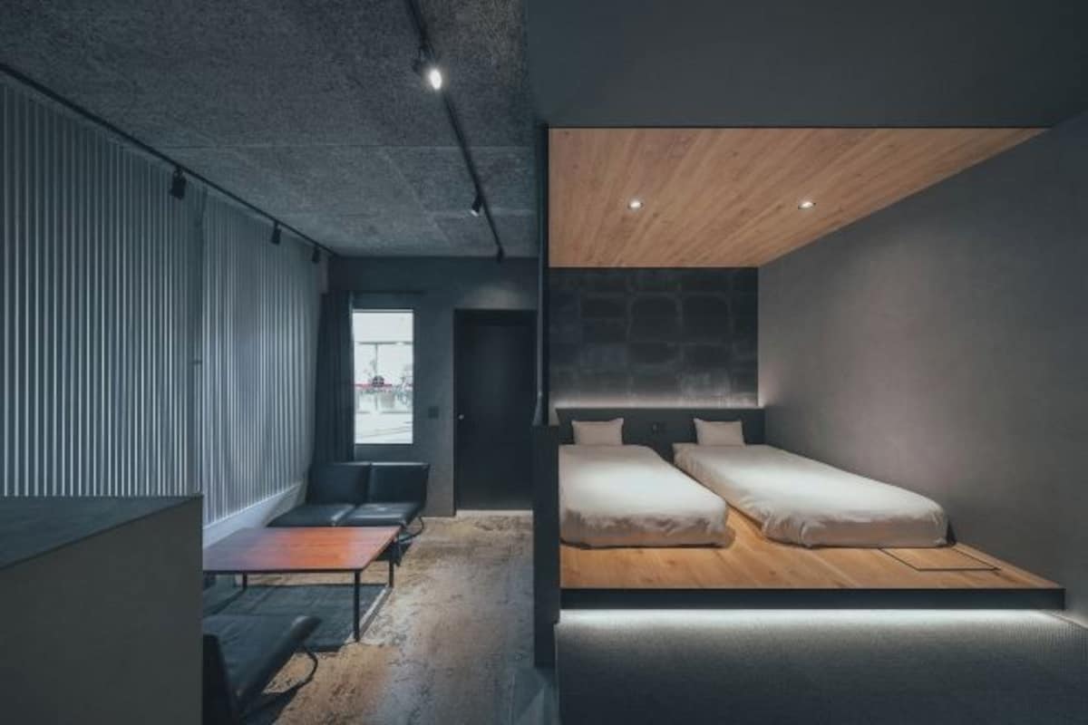 Habitació d'hotel moderna amb disseny minimalista, que destaca per un llit gran, un escriptori petit i una vista per la finestra.