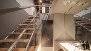 A modern bathroom with a wooden staircase, a large mirror, and a sink with modern fixtures. - SEKAI HOTEL Deep Osaka Experience - Hostel (Higashi-osaka)