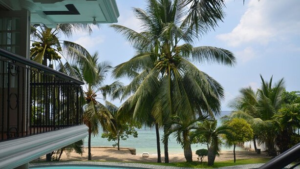 A poolside view with a beach and palm trees. - Robinland Vacation Home Badian (Alegria)