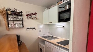 Een kleine keuken met een spoelbak, een magnetron en een wasmachine.