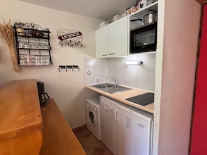 Eine kleine Küche mit Spüle, Mikrowelle und Waschmaschine.