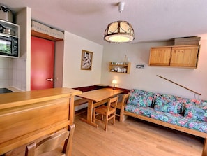 A compact living space with a kitchenette, a dining area, and a sofa.