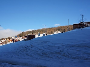 Ein verschneiter Skipisten mit Gebäuden und Bäumen im Hintergrund.