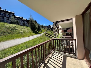 Ein Balkon mit Blick auf eine Straße und Grünflächen, der einen Hügel mit Gebäuden überblickt.