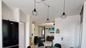 Eine moderne Küche mit einem schwarzen Kühlschrank, einem Esstisch mit vier Stühlen und Pendelleuchten.