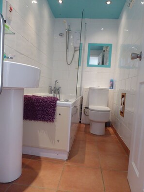 Une salle de bain avec un lavabo, une baignoire et des toilettes, le tout de couleur blanche.