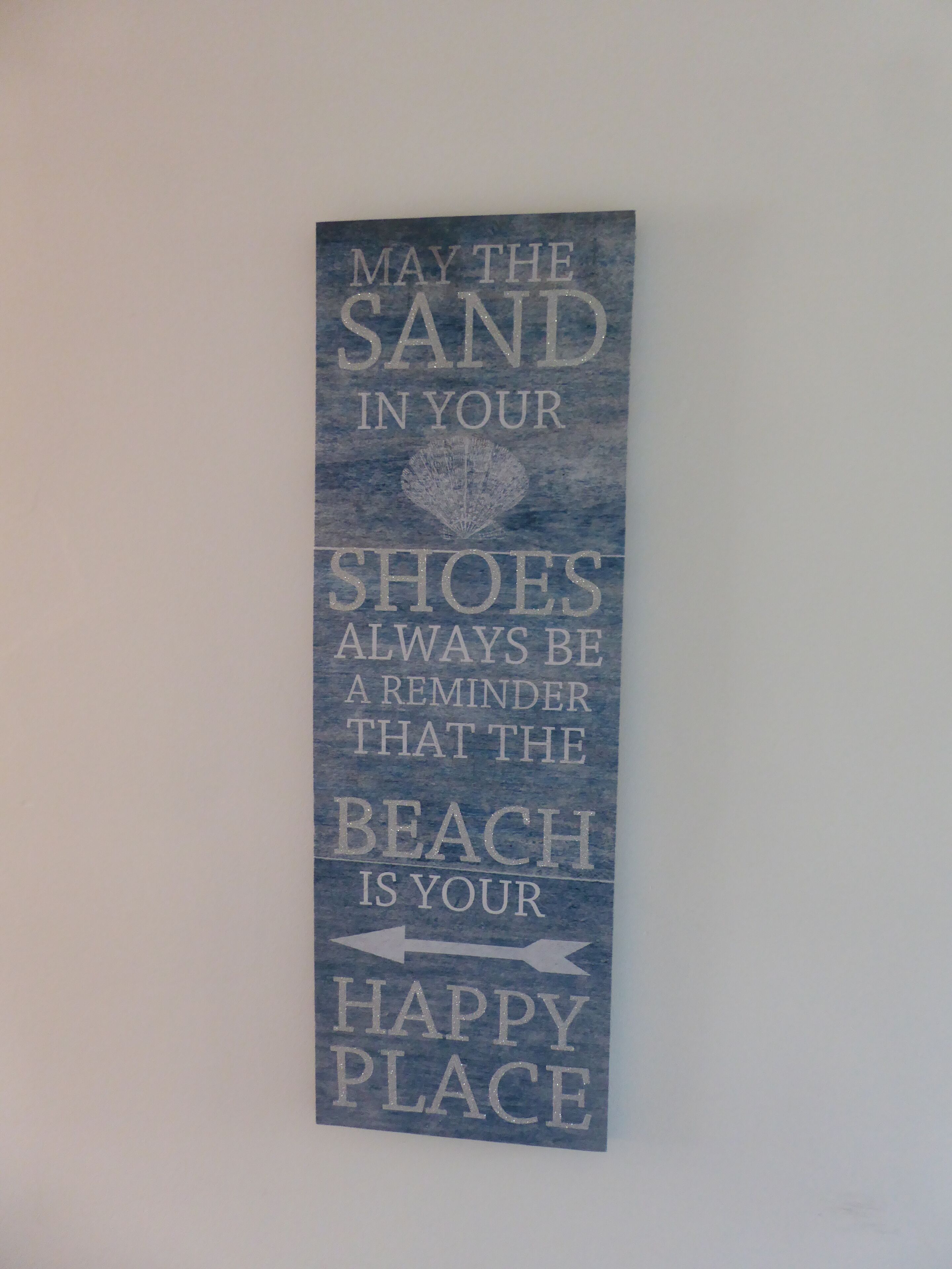 A vertical sign with the text "May the sand in your shoes always be a reminder that the beach is your happy place."