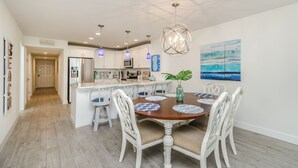 Una cocina amplia con armarios blancos, una isla central e iluminación colgante.