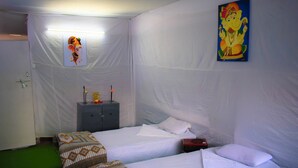 A room with two beds, a nightstand, and a wall painting. - Kumbh Canvas (Prayagraj)