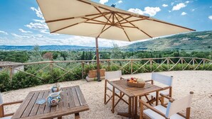 Un área de estar al aire libre con una mesa, sillas y un paraguas grande.