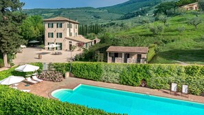 Una villa con piscina, mobiliario de exterior y vistas a colinas ondulantes.