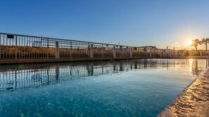A clear pool with a metal railing, a wooden deck, and a sunset in the background. - Beautifully Condo BOOK TODAY (Navarre)