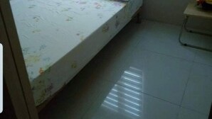 Une petite chambre avec un lit simple, une fenêtre et une table de chevet.