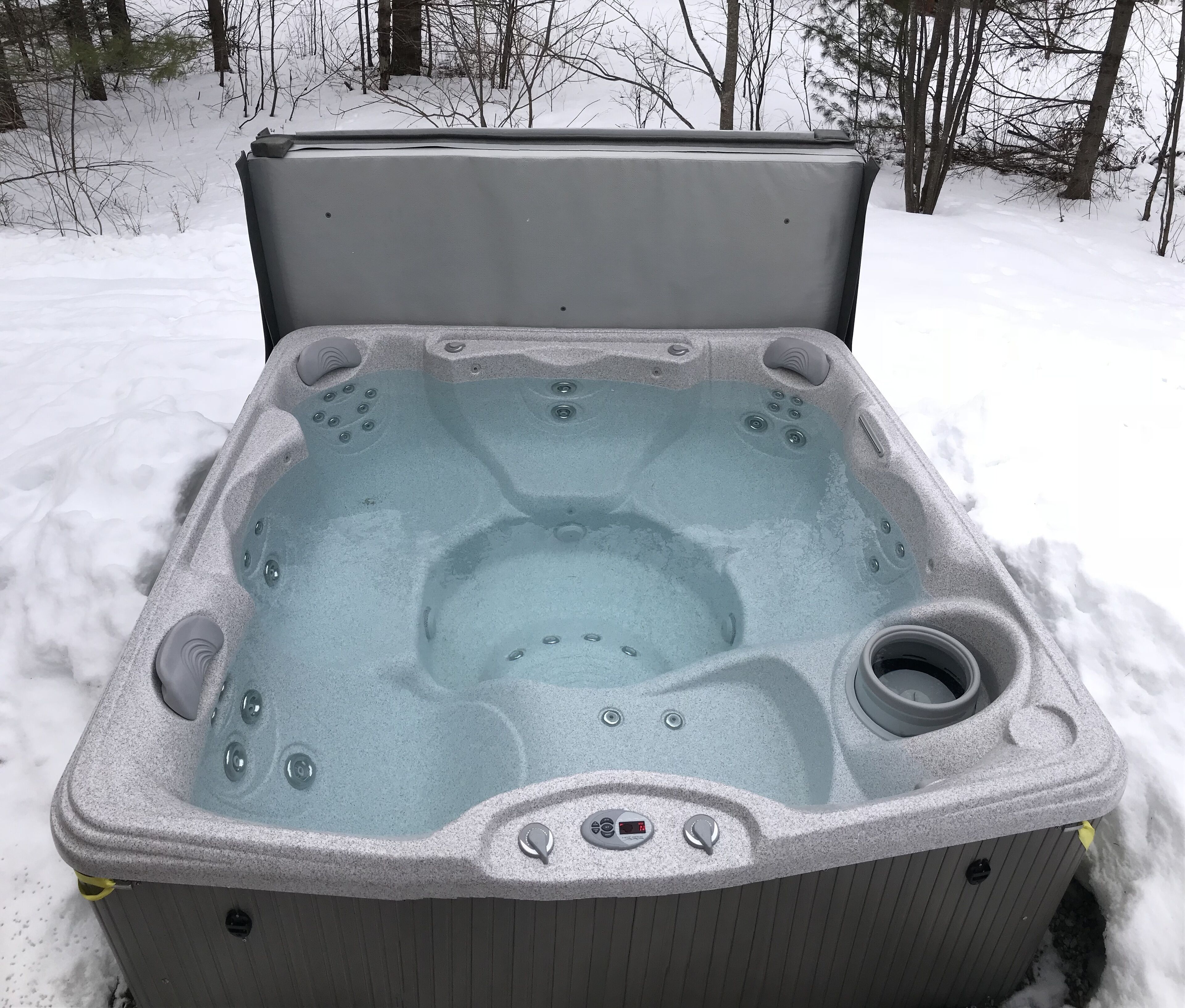 A hot tub with a control panel, a drain, and a built-in seat.