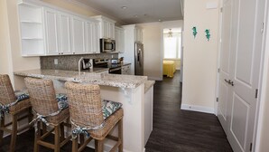 A kitchen with white cabinets, a granite countertop, and a central island with bar stools. - Stunning & Welcoming Pool Home on Canal (Marathon)