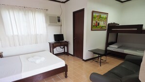 A room with a bed, a sofa, a small table with a TV, and a door. - Balay Travel Lodge (Paoay)