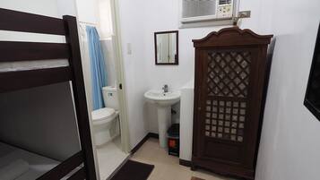 A compact room with a bunk bed, a small sink, a toilet, and a wardrobe with a lattice design.