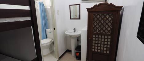 Quarto compacto com beliche, pia pequena, vaso sanitário e guarda-roupa com design vazado.