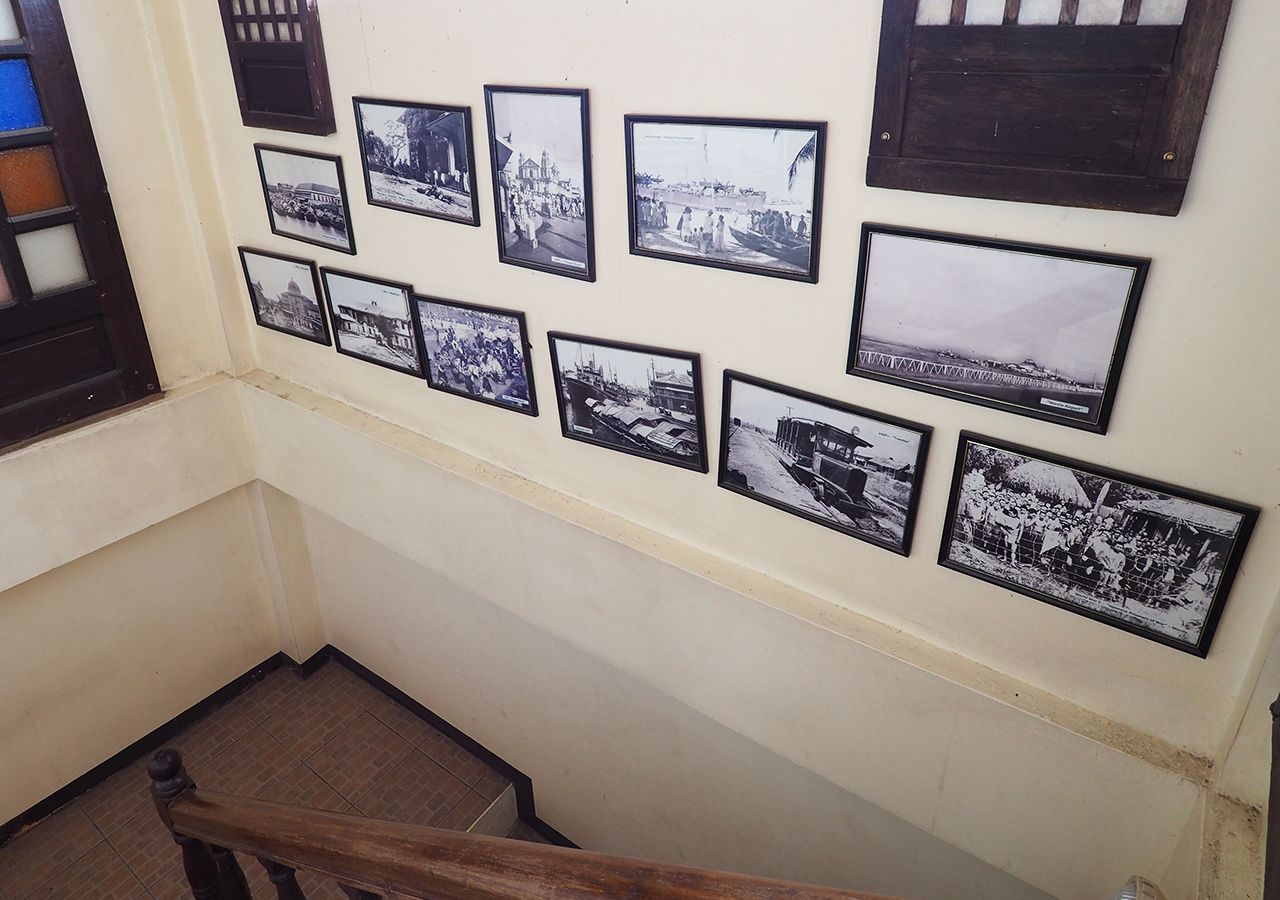 A staircase with a wooden handrail and a wall adorned with black and white photographs.