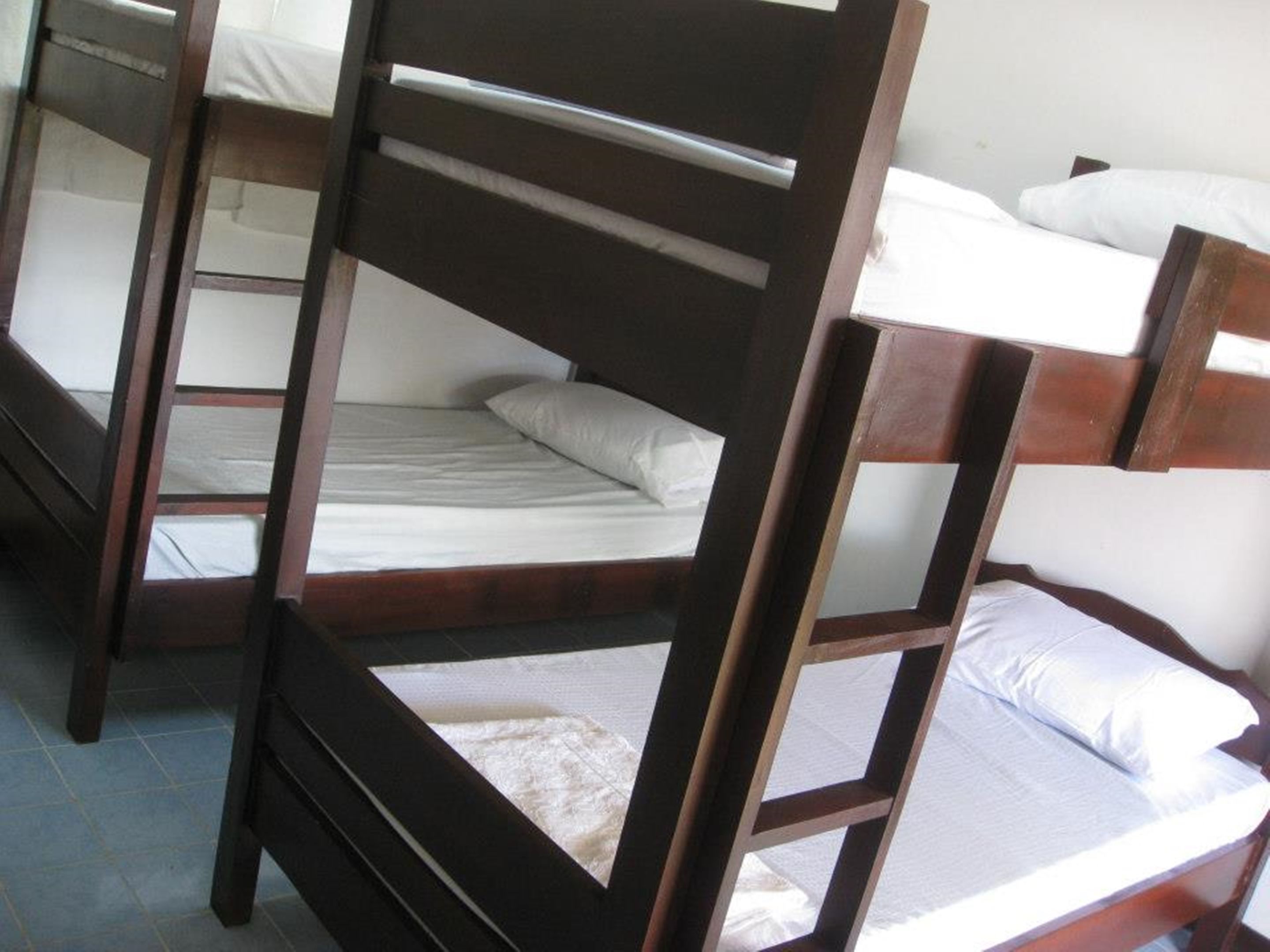 A set of wooden bunk beds with white bedding.