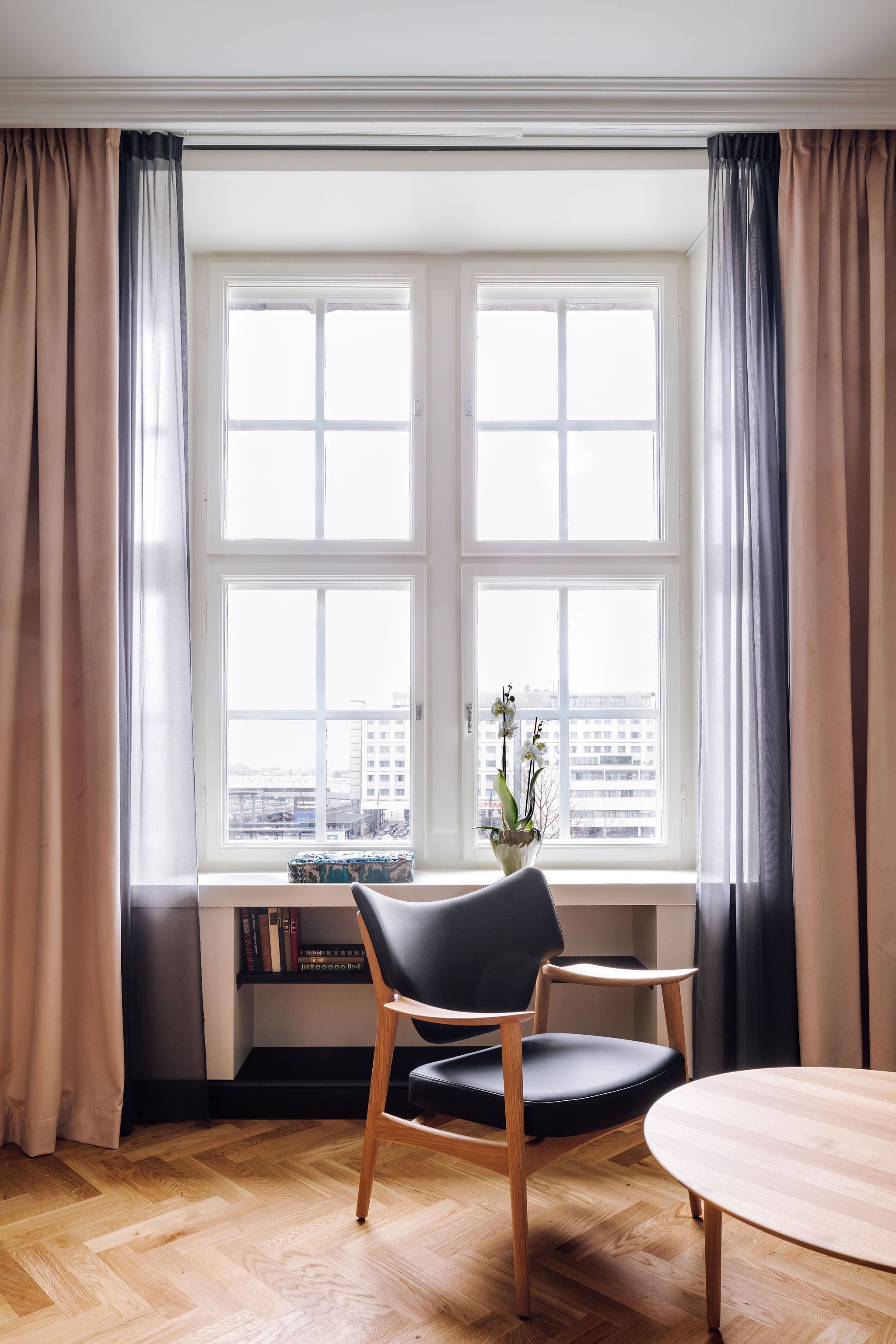 A room with a large window, a chair, a table, and a bookshelf.