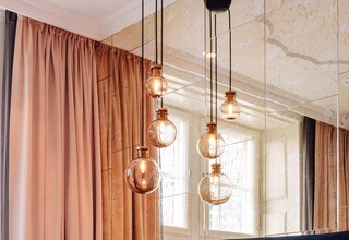 A hotel room with a large bed, a headboard, and multiple hanging pendant lights.