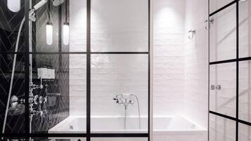 A modern bathroom with a glass shower enclosure, a separate bathtub, and a vanity with a mirror.