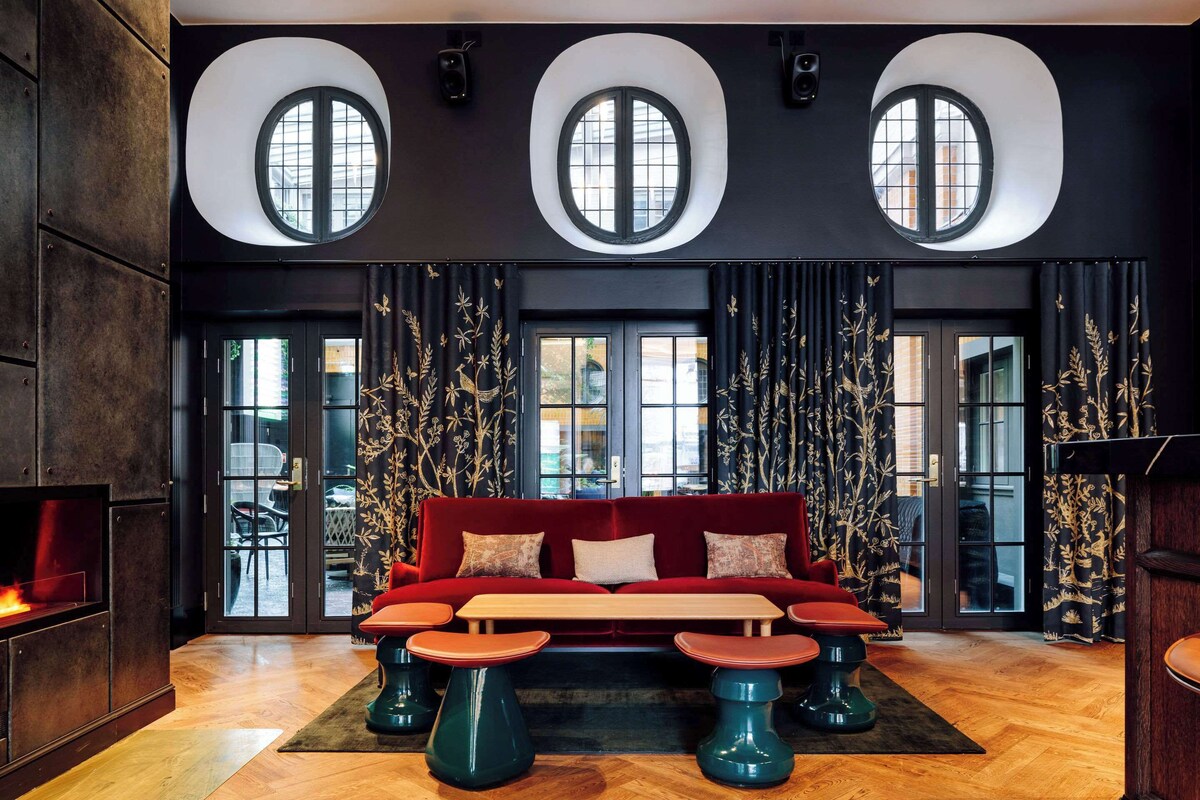 Dark hotel lobby with red velvet couch and circular windows