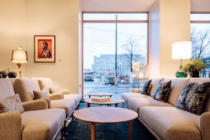 A modern living room with a sofa set, a coffee table, and a large window offering a view of the cityscape.