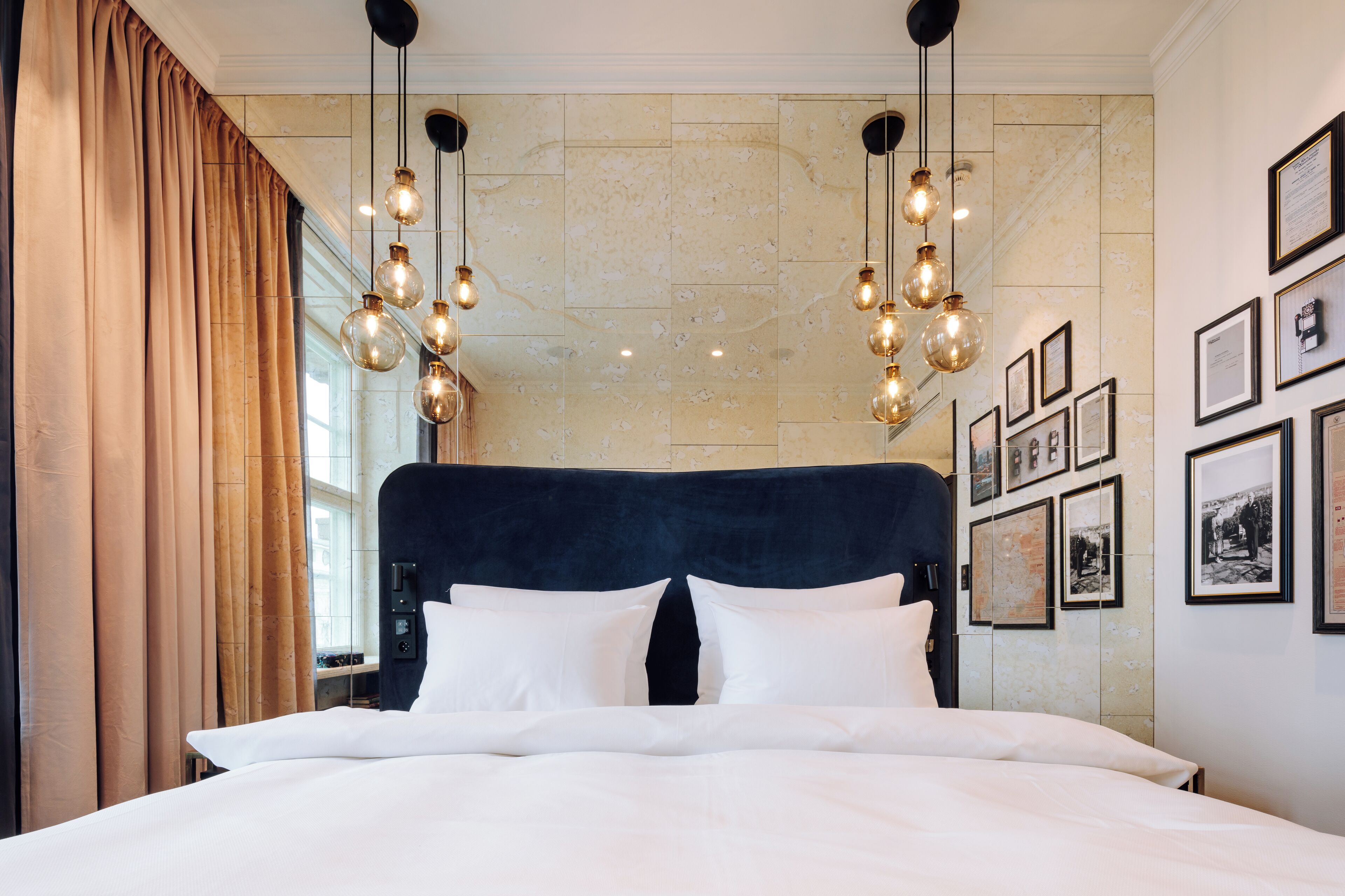 A hotel room with a large bed, a dark headboard, and multiple framed pictures on the wall.