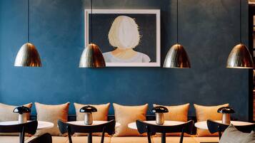 A modern interior with a blue wall, a framed artwork, and a seating area with tables and chairs.